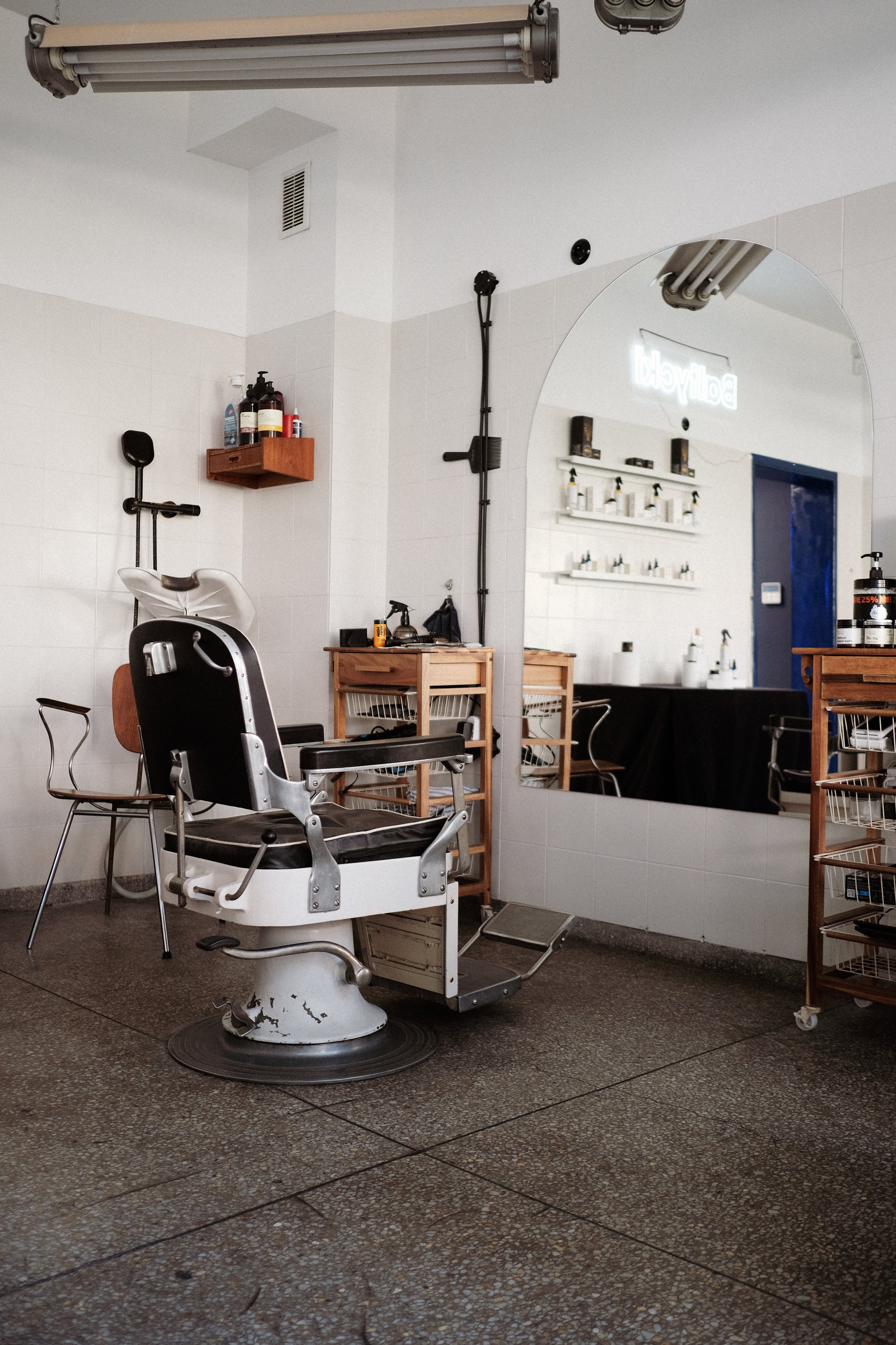 Salon barberski z czarnym fotelem i lustrem na przeciwko 
