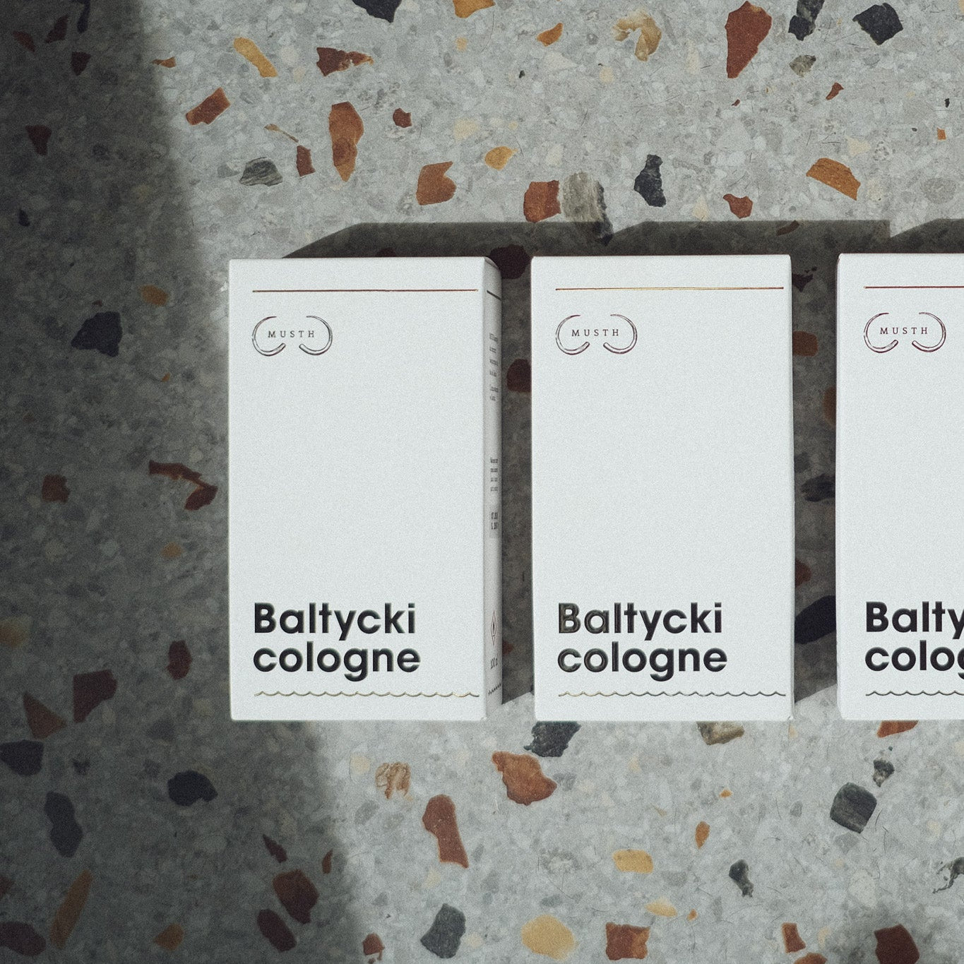 Trzy opakowania baltycki cologne na tle lastryko