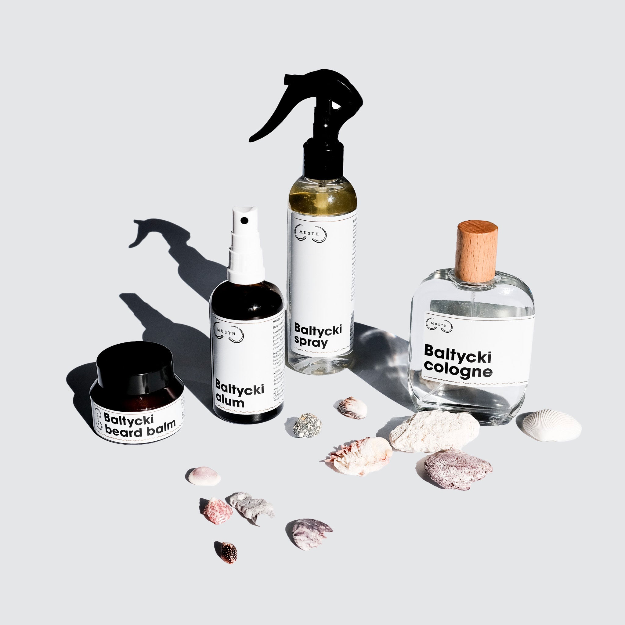 Słoiczek balsamu do brodu, butelka dezodorantu, butelka sprayu do włosów i butelka wody kolońskiej, muszelki jako ozdoba